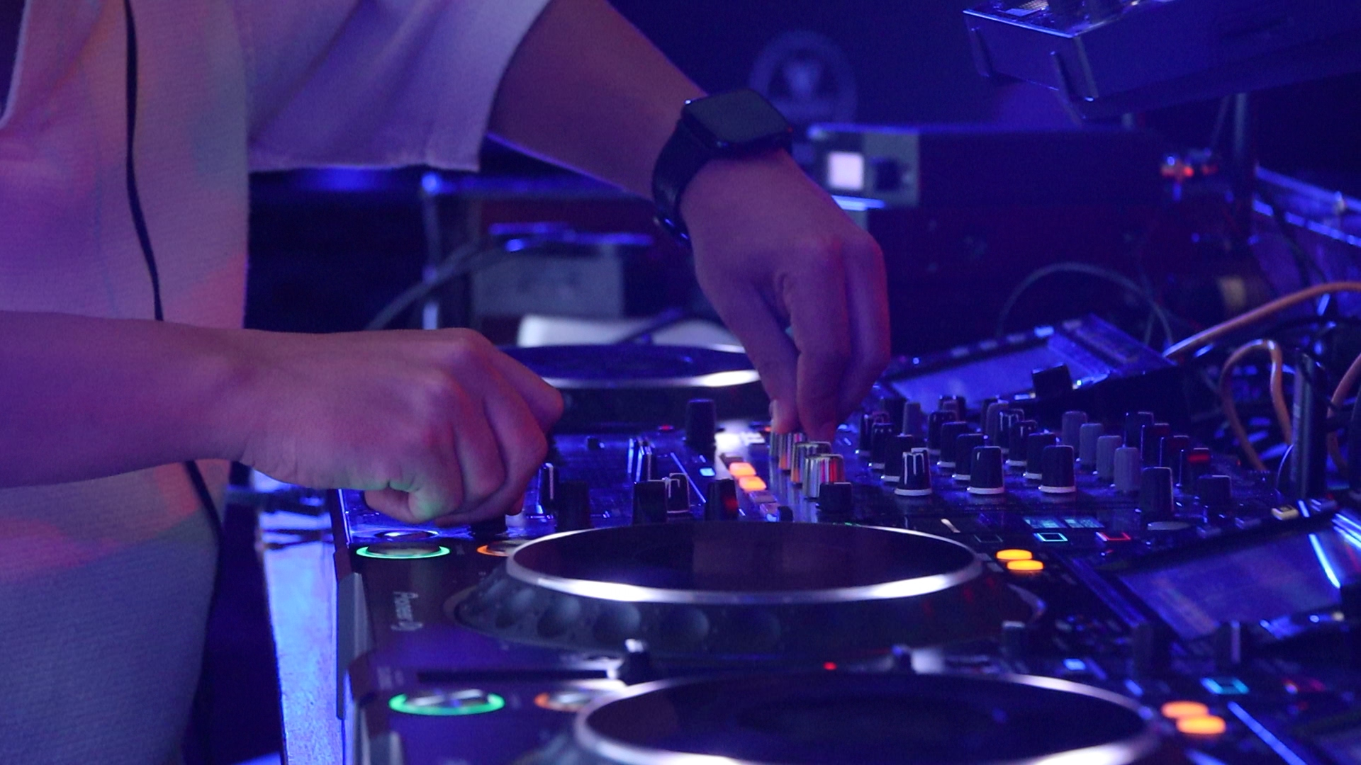 DJ mezclando en cabina con luces moradas y azules